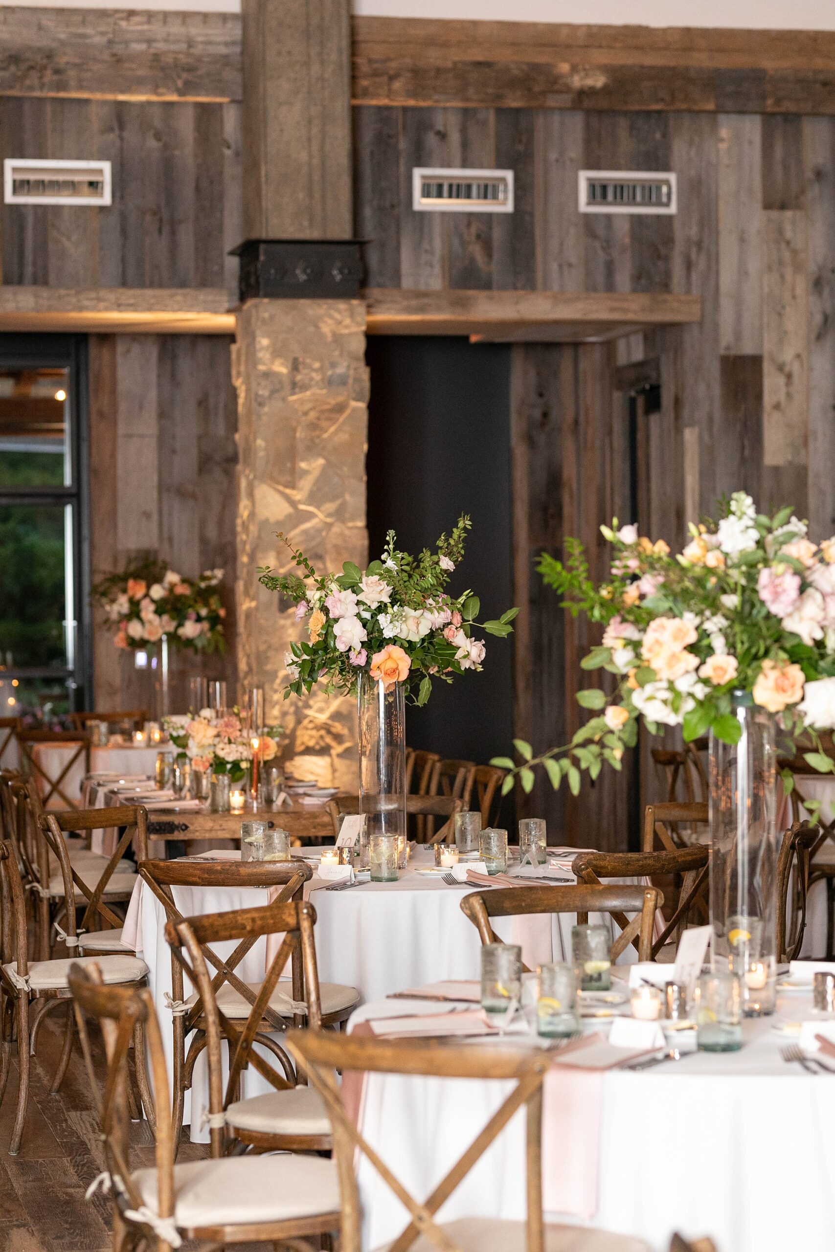 tall floral arrangements on tables for wedding reception in the barn at the Hotel Drover