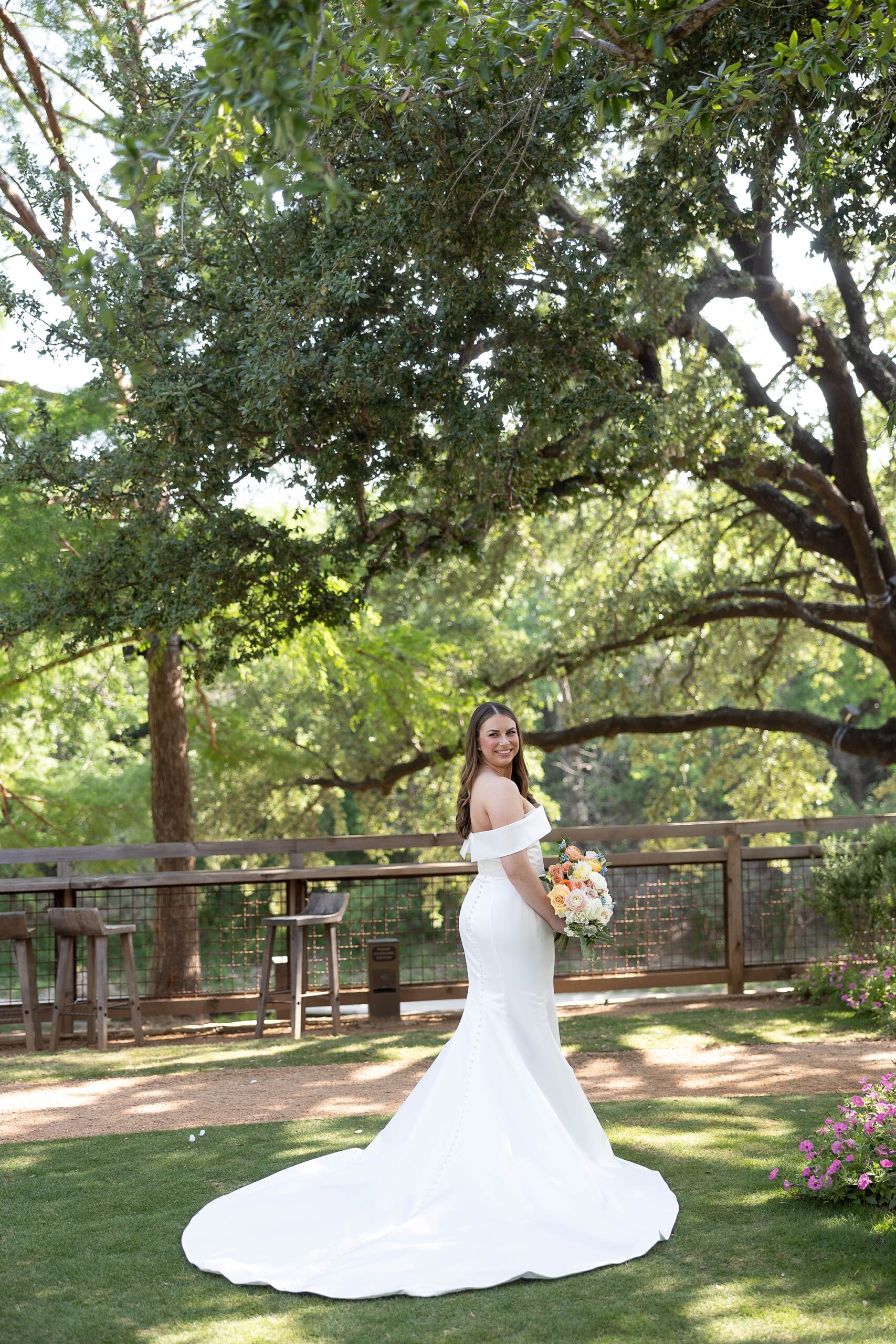 bride poses in garden of the Hotel Drover in off-the-shoulder wedding gown