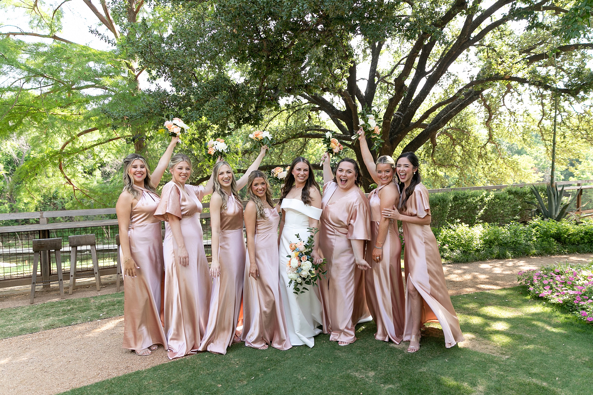 bride and bridesmaids in pink gowns cheer on lawn at the Hotel Drover