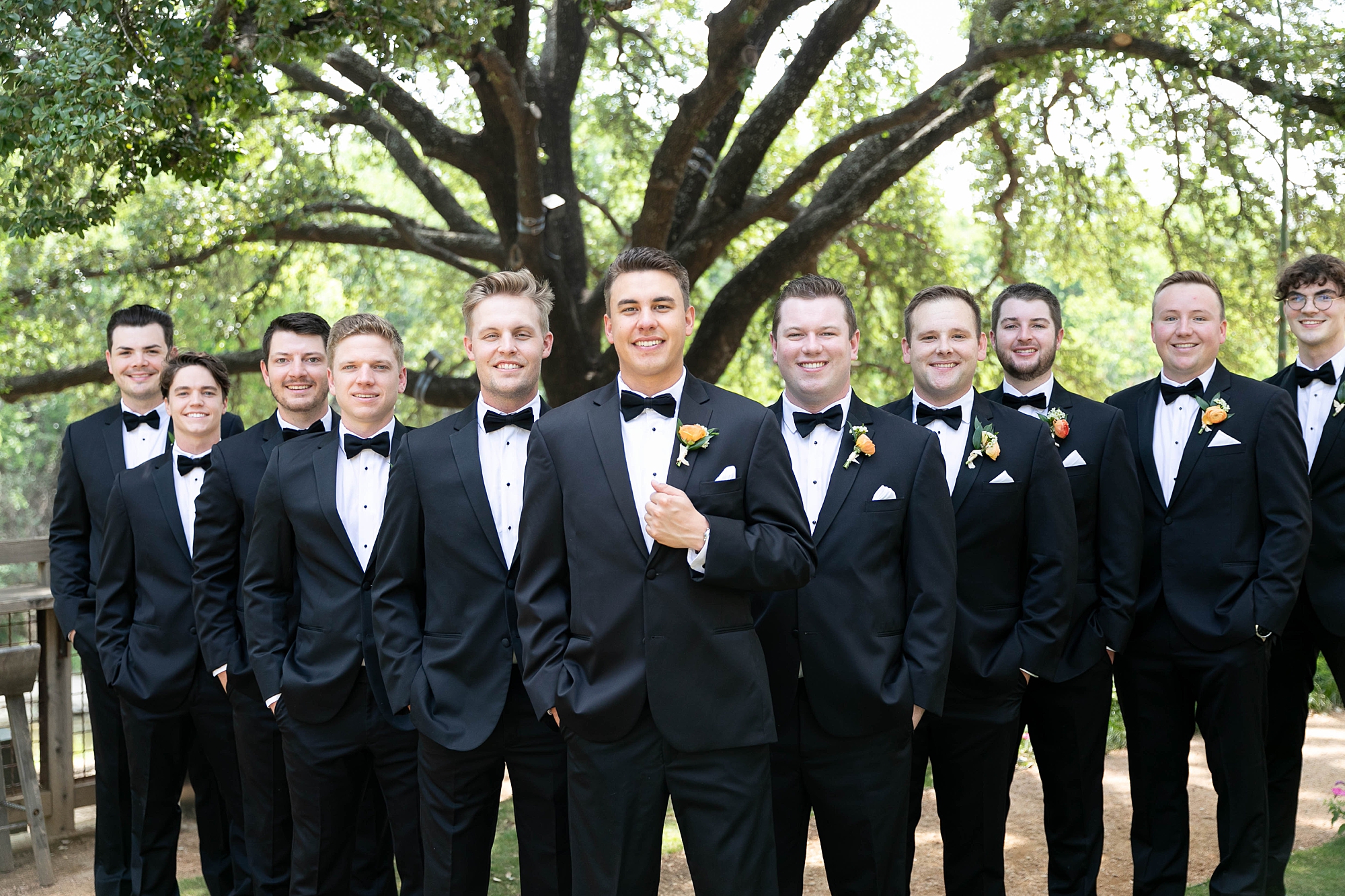 groom stands in front of v-formation of groomsmen at the Hotel Drover