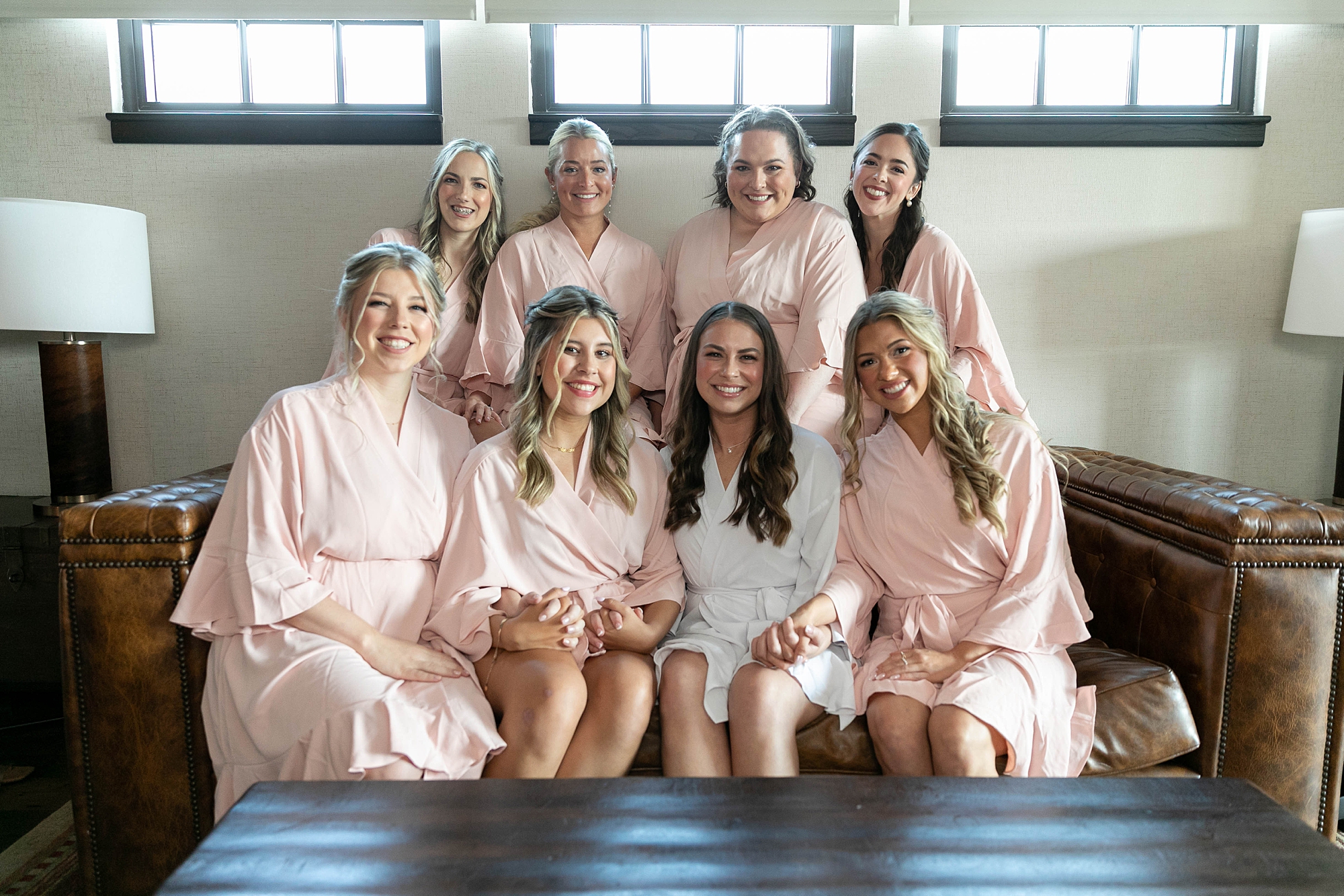 bride sits with bridesmaids in pink robes inside the Hotel Drover