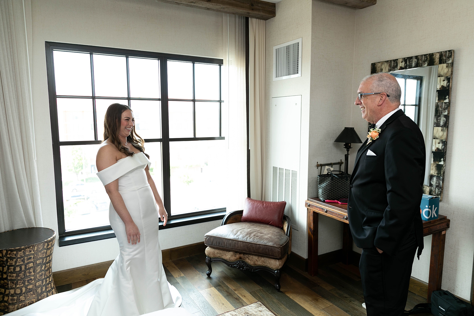 bride looks at father showing off gown during first look 