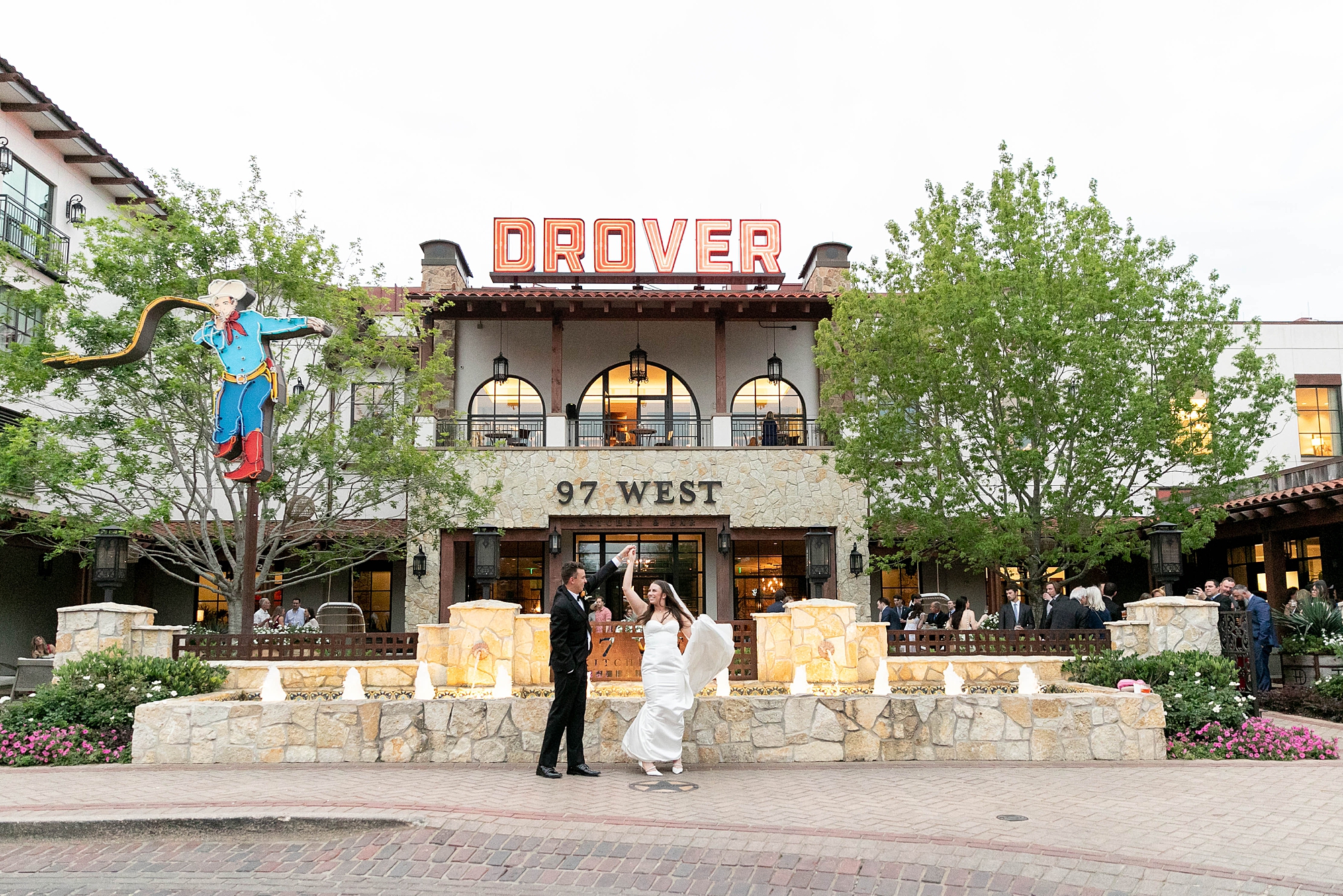 groom twirls bride on wedding day outside the Hotel Drover