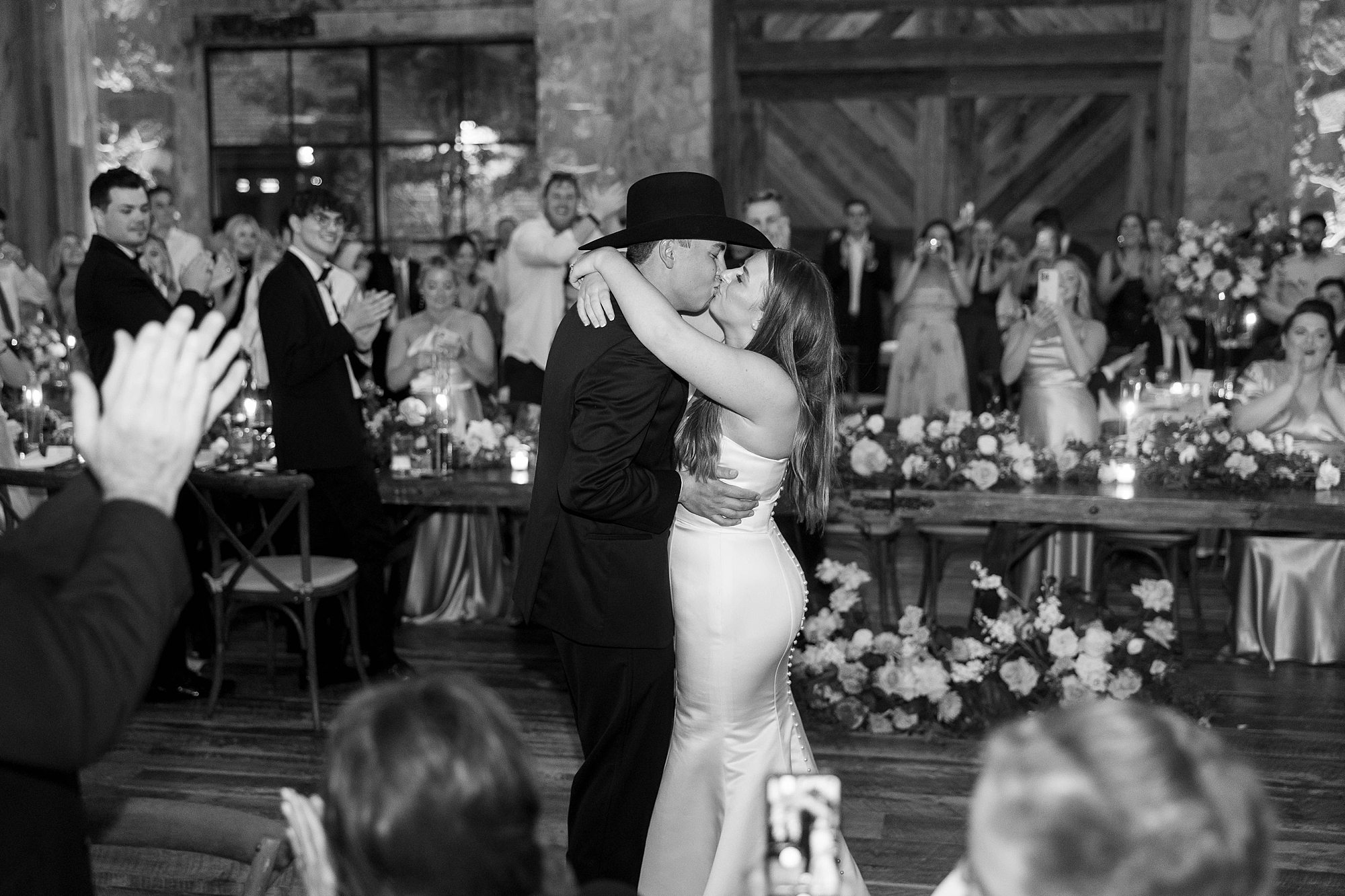 newlyweds kiss on dance floor during wedding reception in the barn at the Hotel Drover