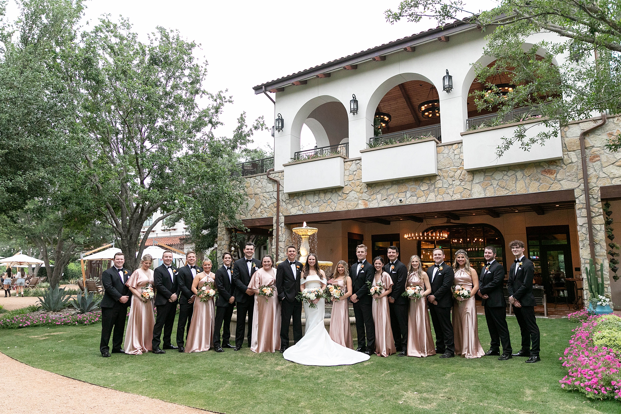 bride and groom stand with wedding party outside the Hotel Drover