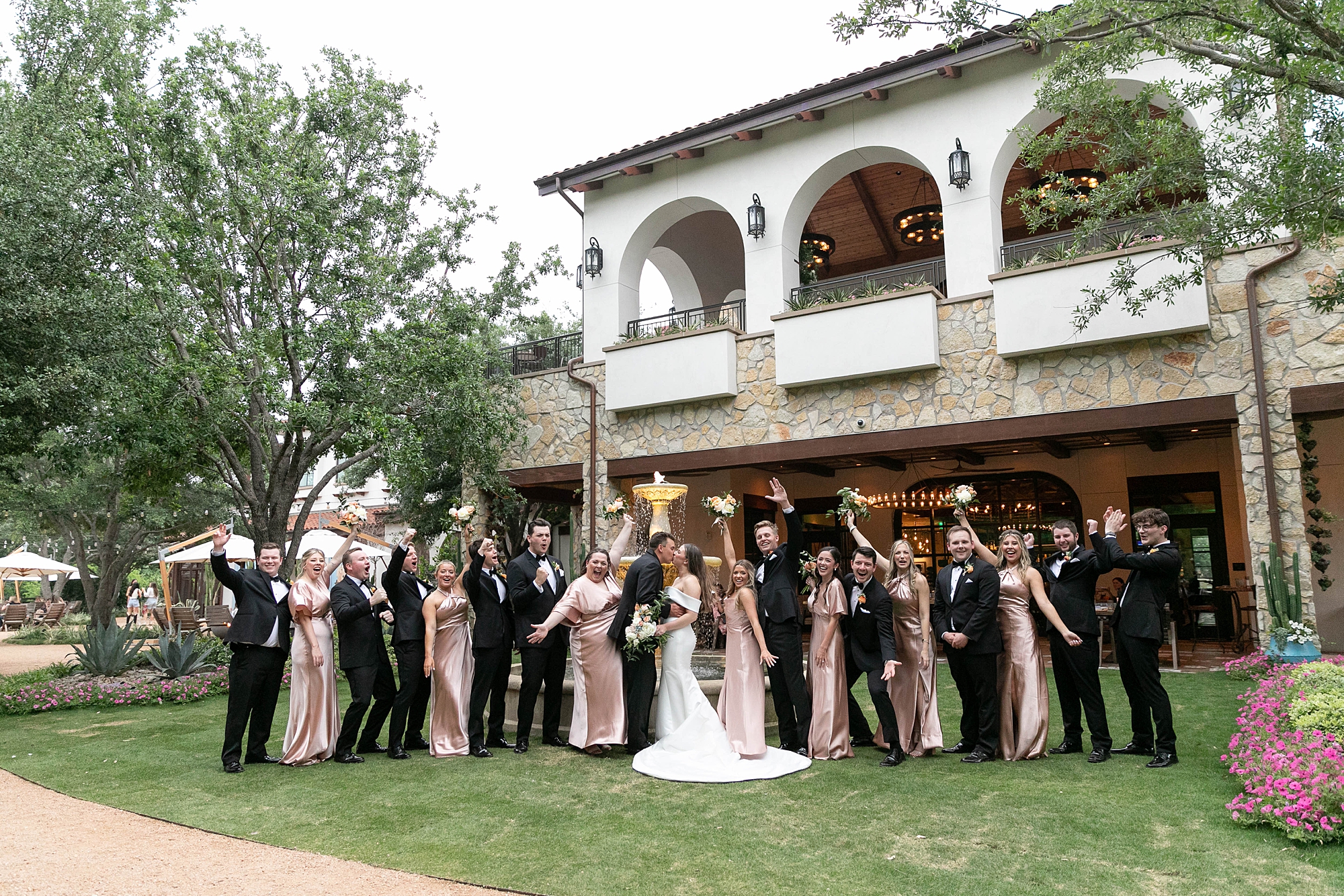 newlyweds kiss while wedding party cheers in front of the Hotel Drover