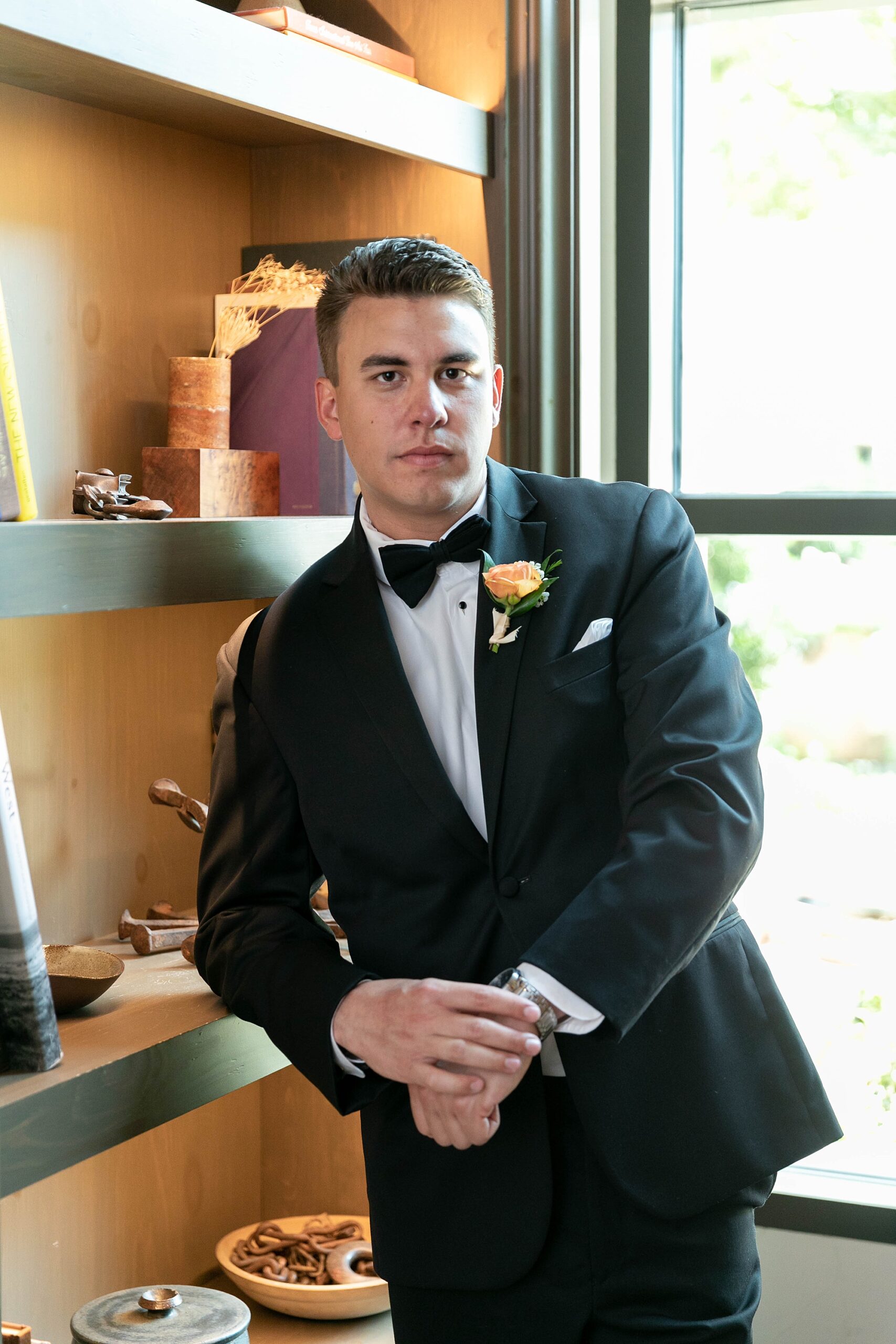 groom leans against shelf in suite at the Hotel Drover