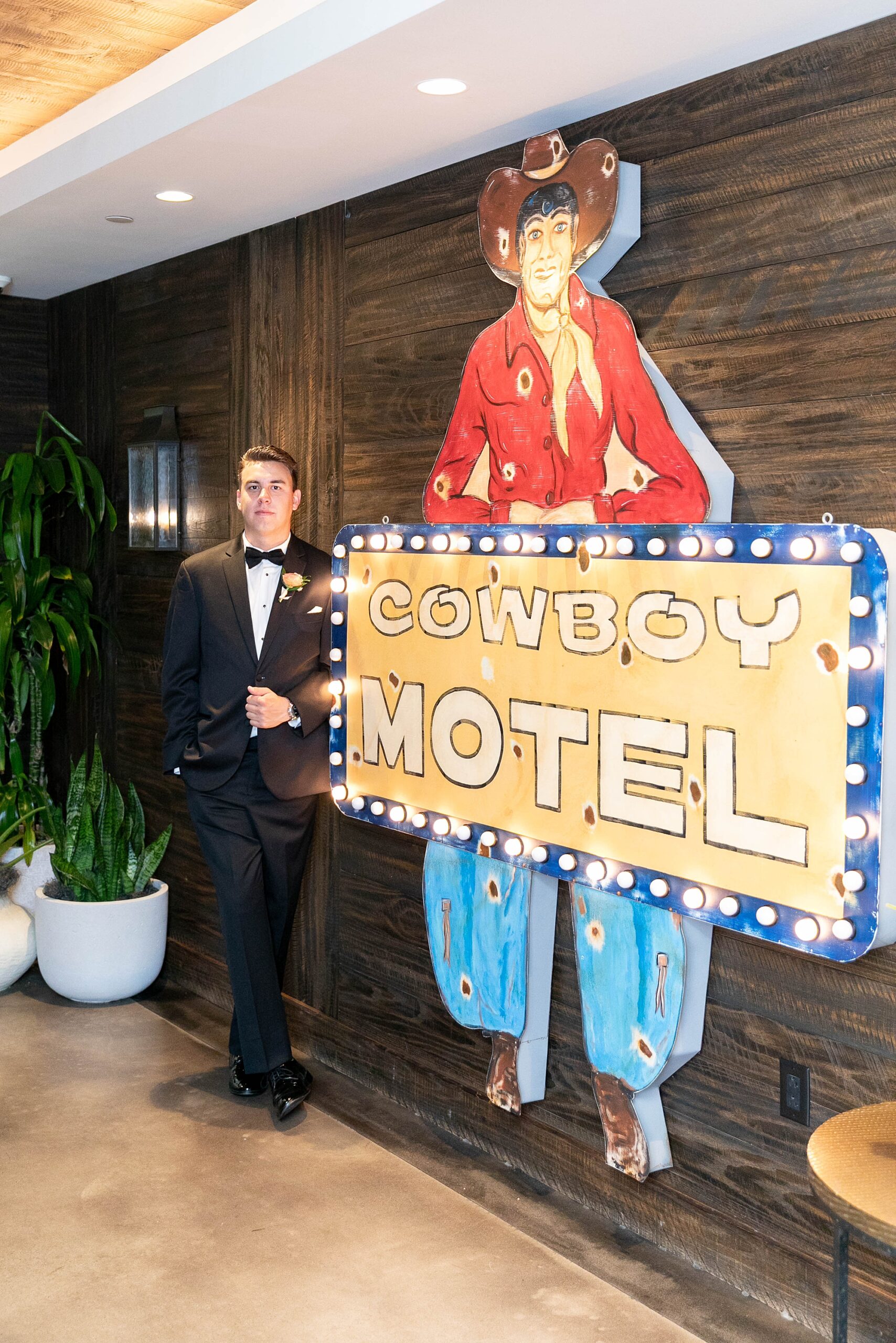groom stands by sign that says "cowboy hotel" at the Hotel Drover