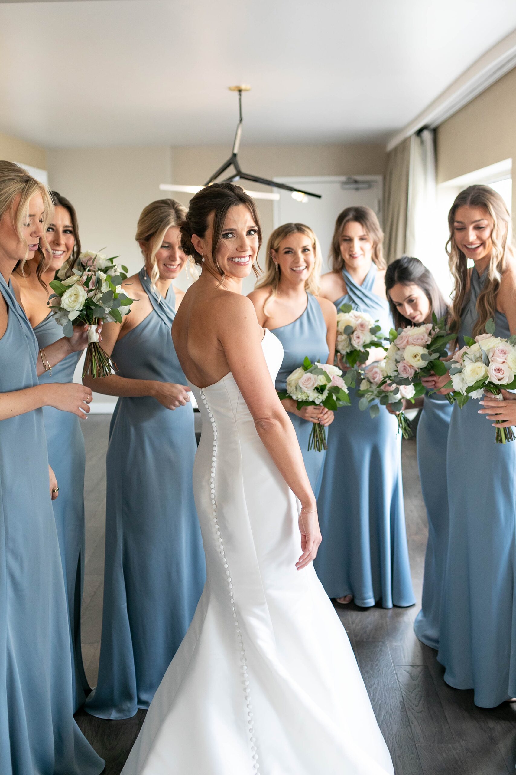 bridesmaids in blue gowns smile at the bride at the Statler Hotel