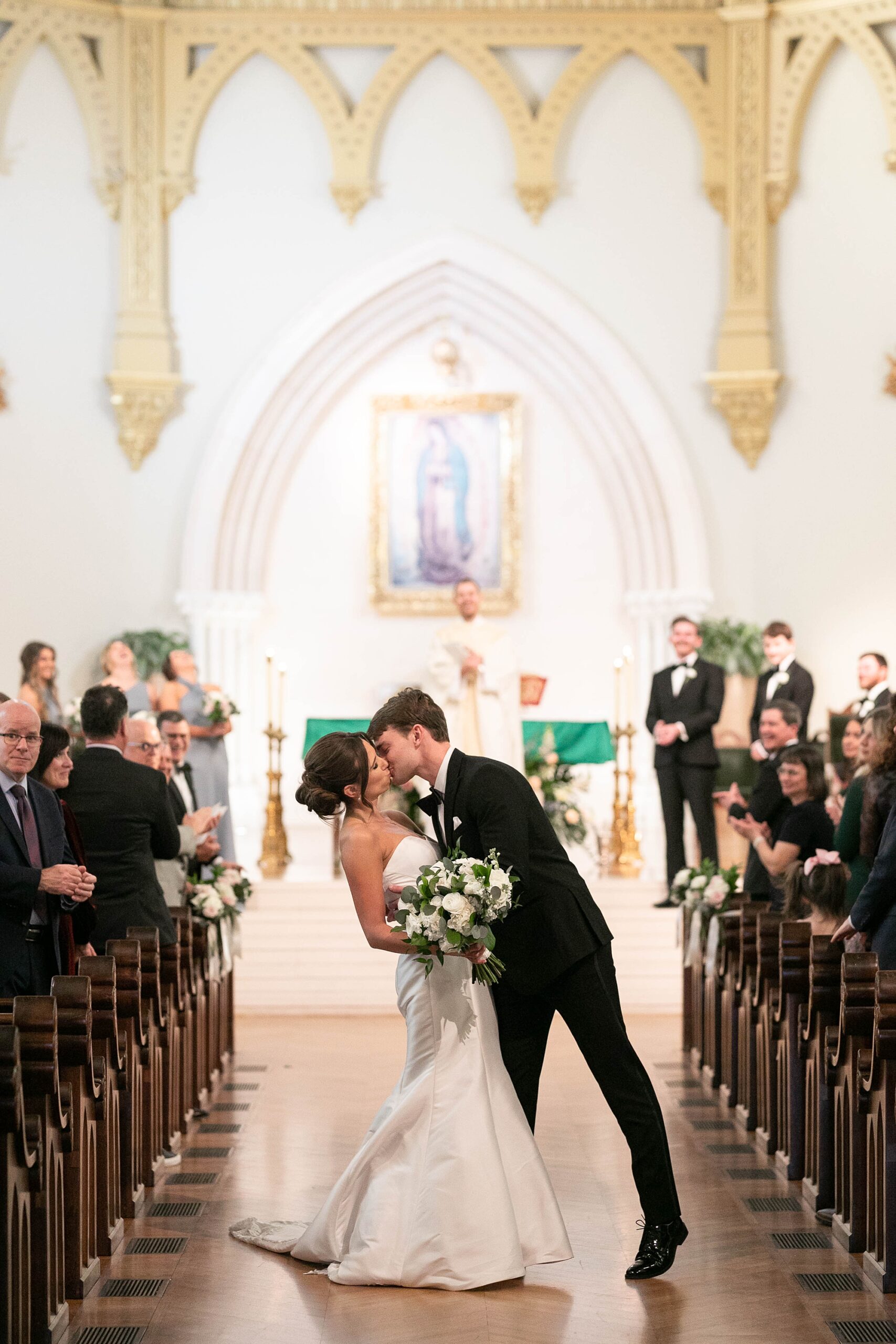bride and groom kiss dipping in the aisle after traditional Catholic wedding at the Cathedral Guadalupe in Dallas TX