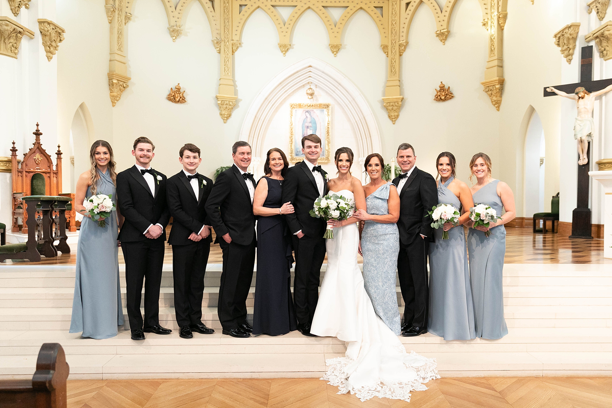bride and groom stand with family in front of alter in Catholic Church 