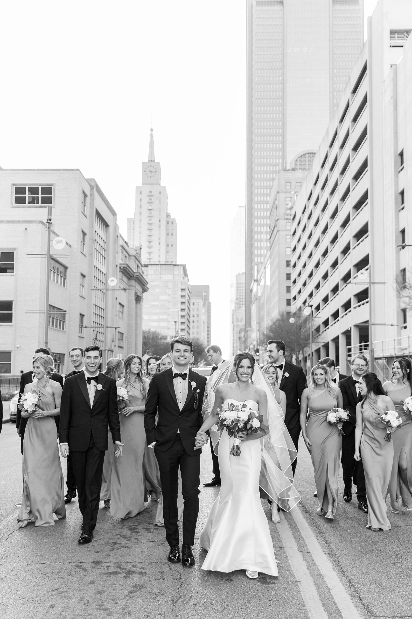 bride and groom hold hands walking with wedding party in Dallas TX