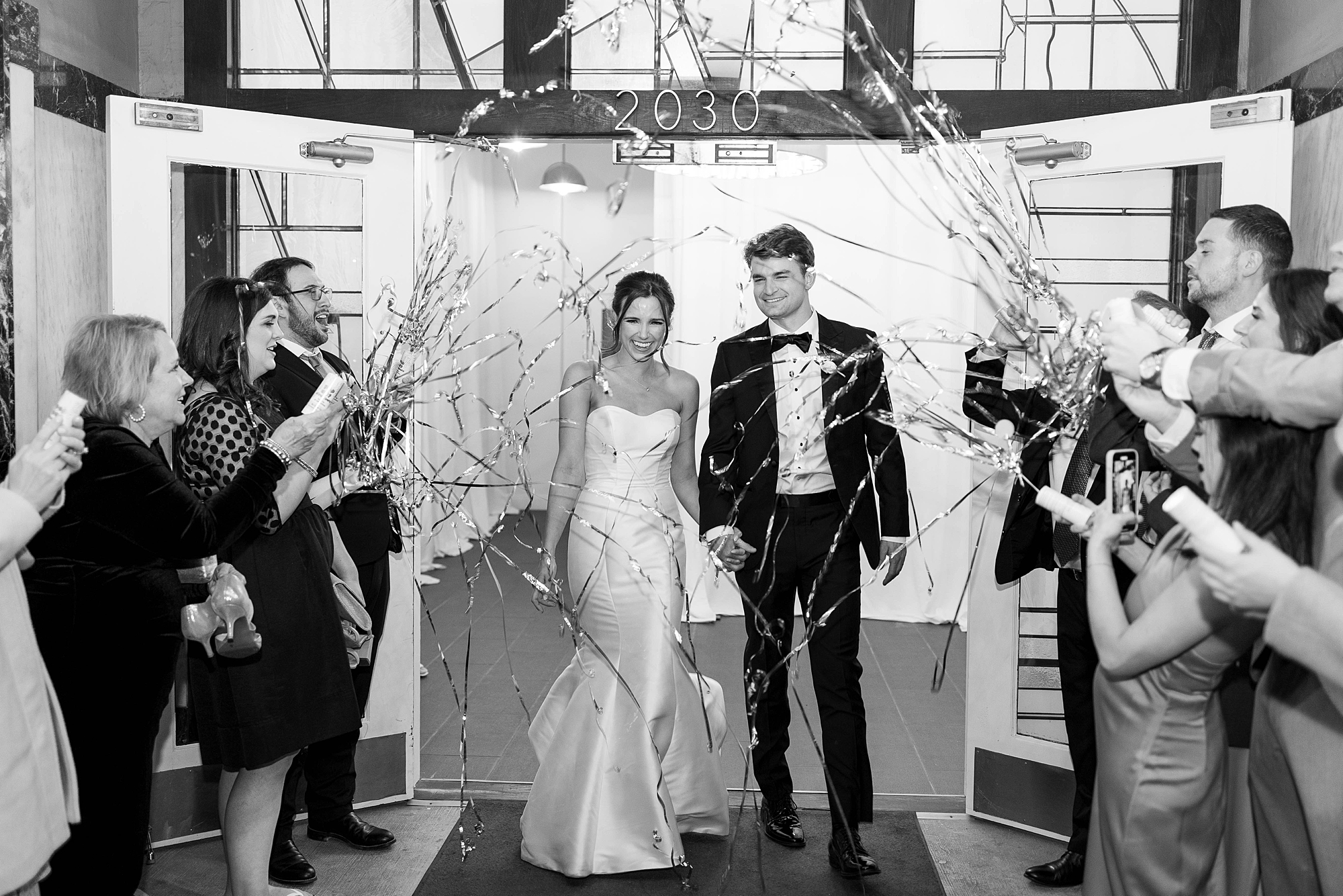bride and groom smile through streamer exit from Dallas venue