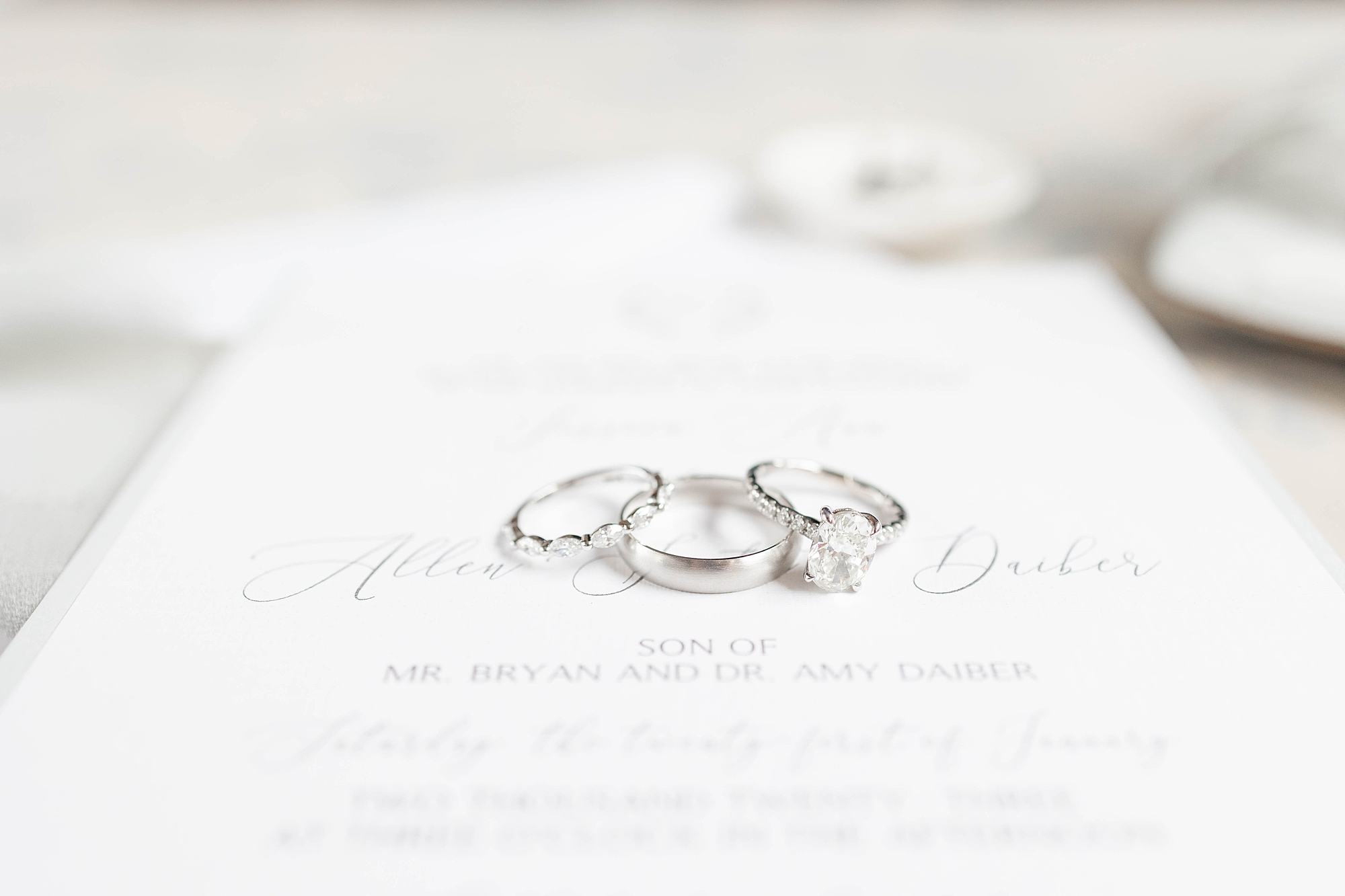 wedding rings lay on white invitation suite 