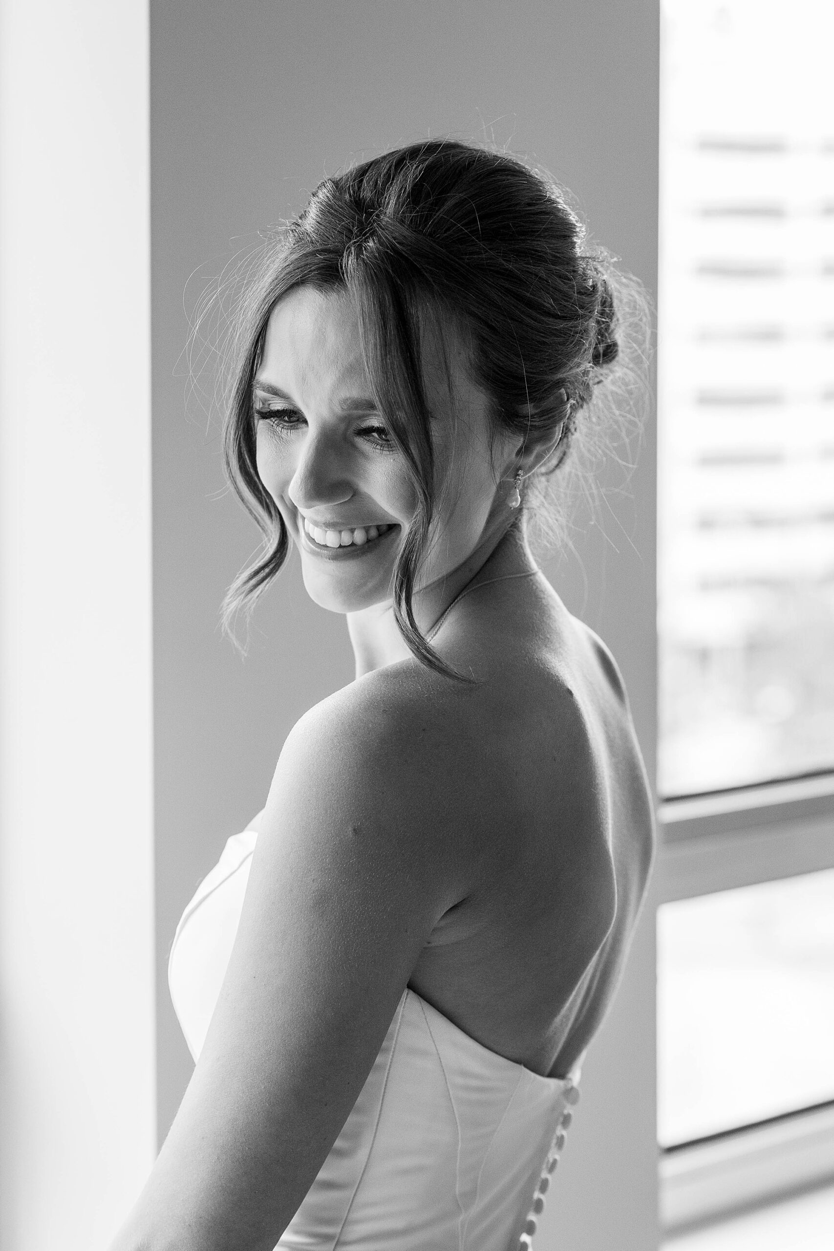 black and white portrait of bride by window in strapless wedding gown