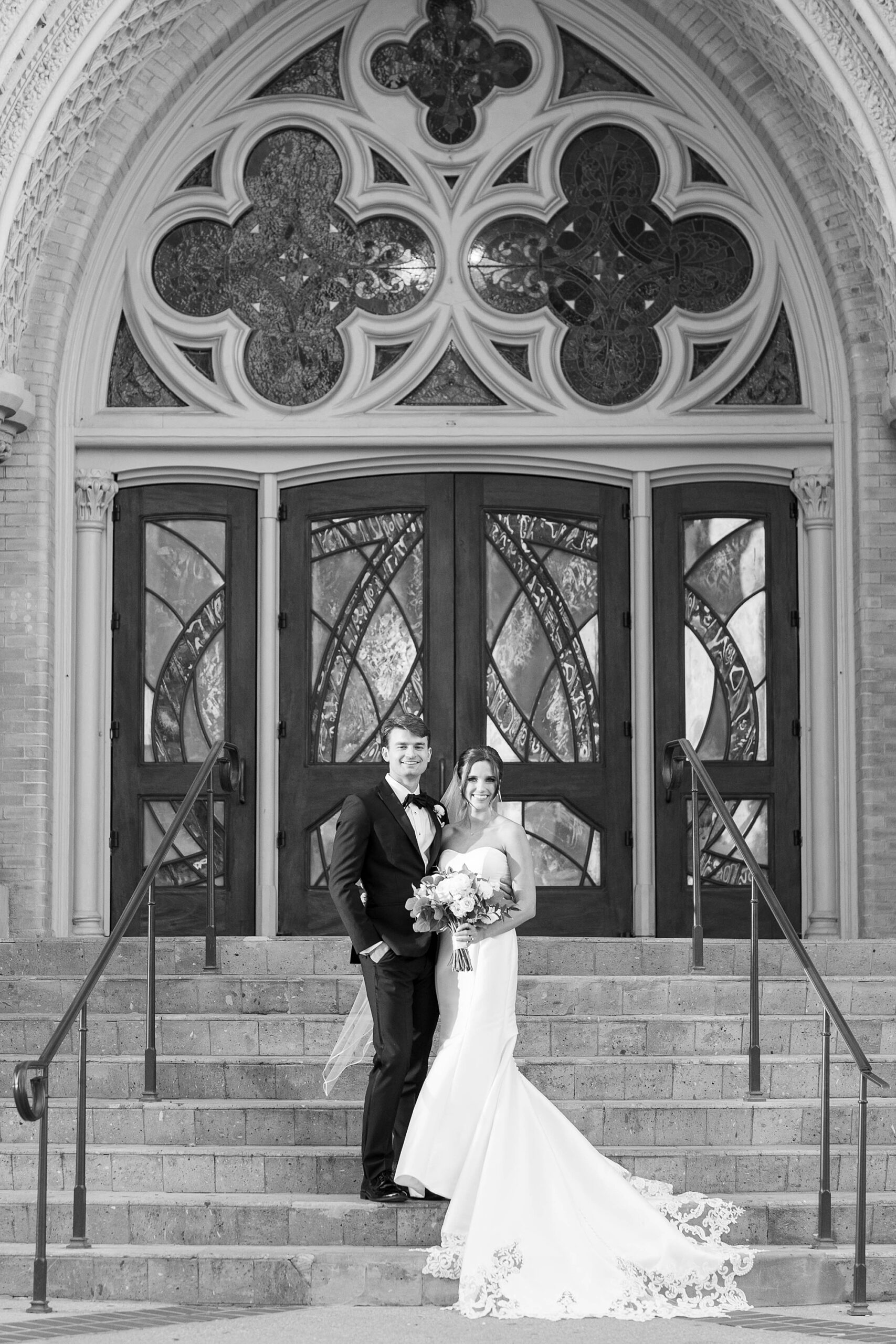 bride and groom stand on front steps at the Cathedral Guadalupe