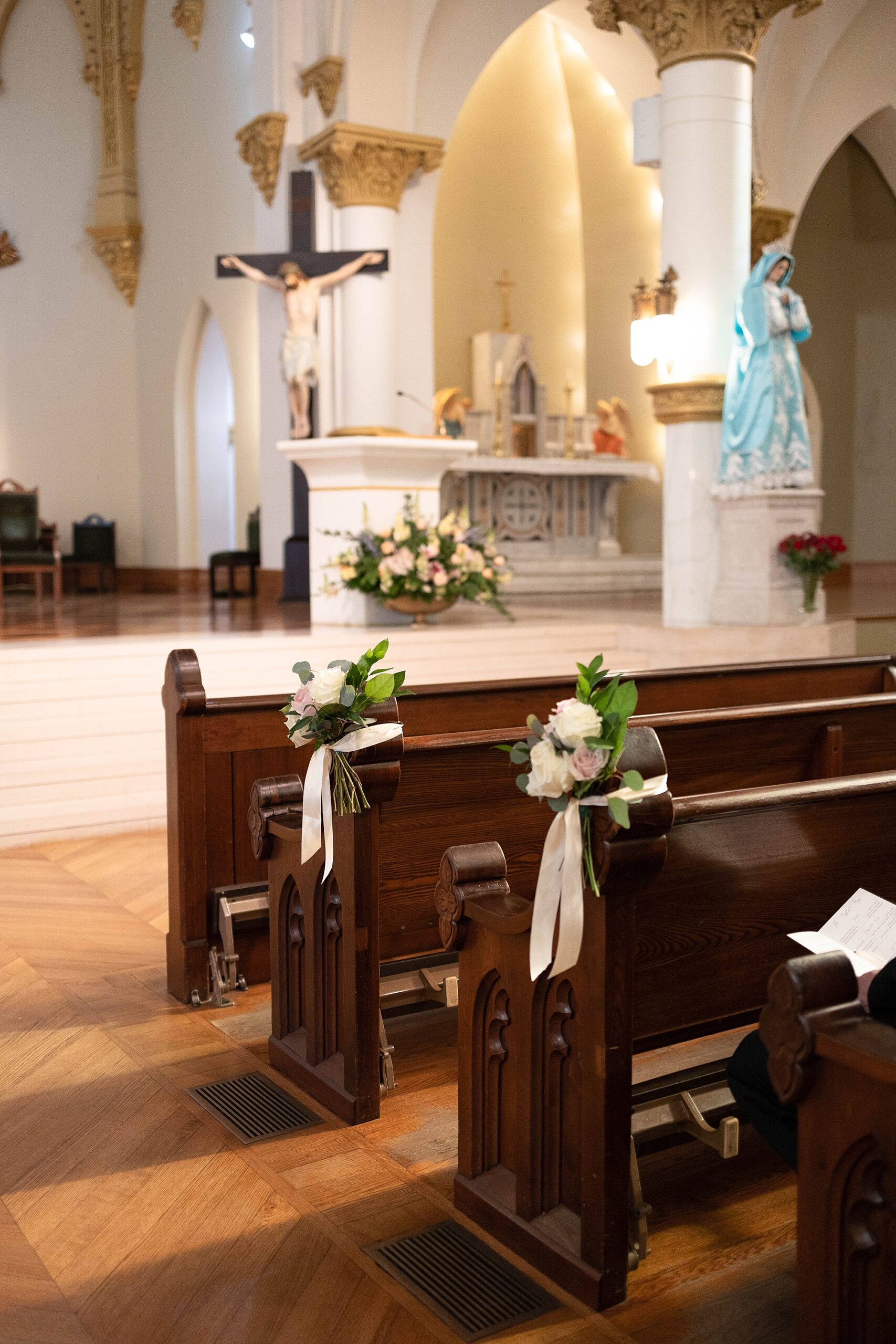 white flowers hang on wooden pews inside Catholic Church 
