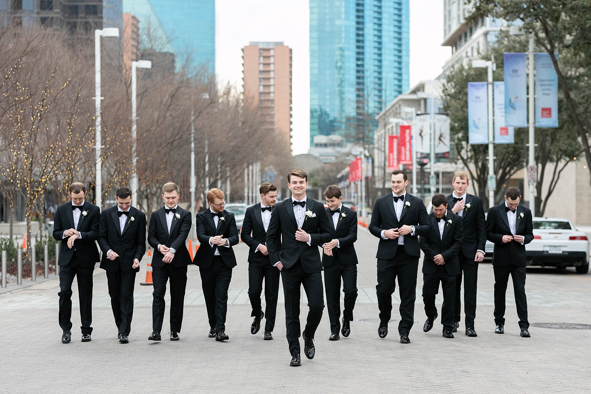 groom walks with groomsmen in black suits in Dallas TX