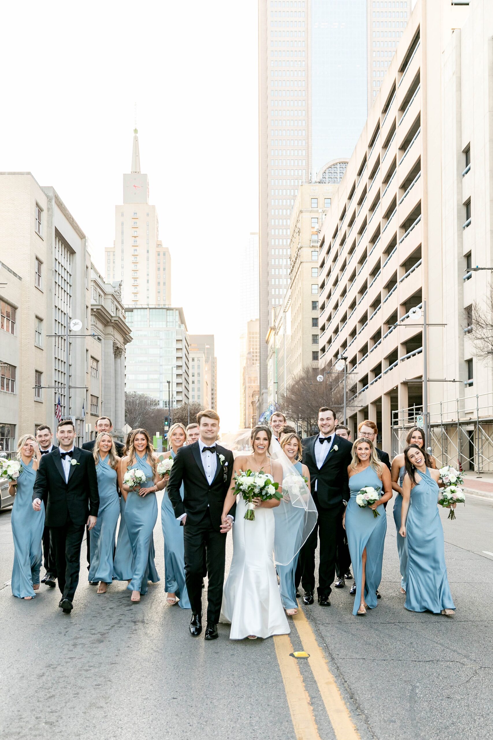 bride and from walk with wedding party down street in Downtown Dallas 
