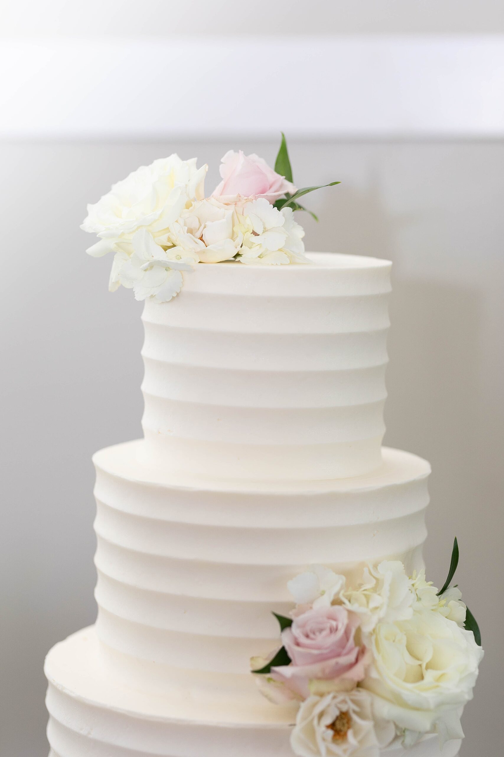 tiered wedding cake with white icing and florals on layers 