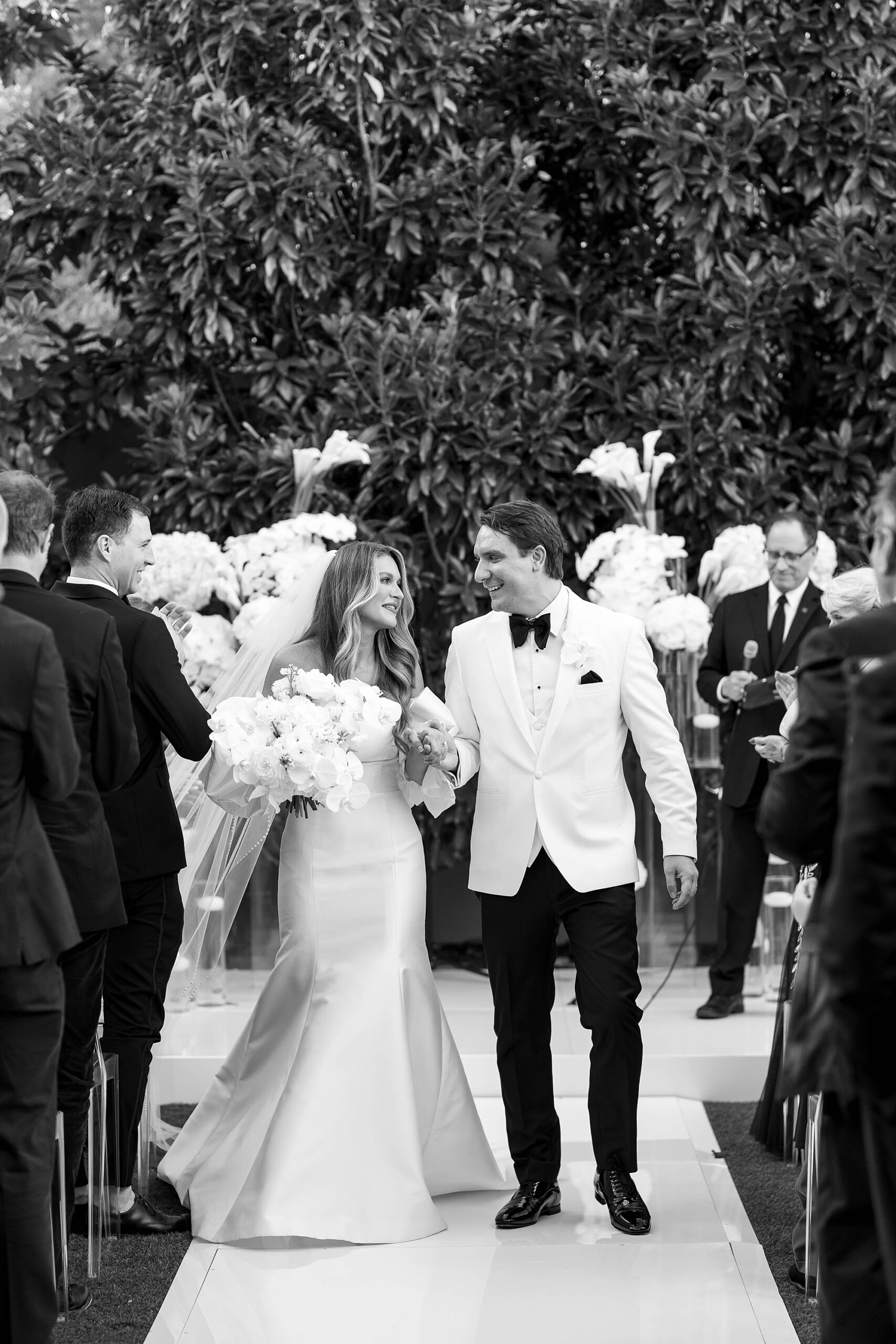bride and groom hold hands walking up aisle after ceremony on lawn at Rosewood Mansion