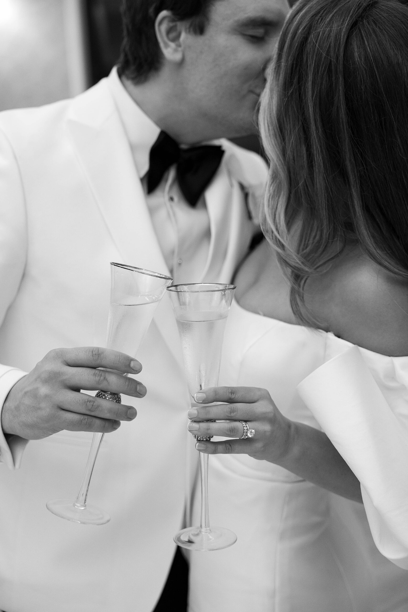 bride  and groom toast gold-rimmed champagne glasses during Dallas wedding day