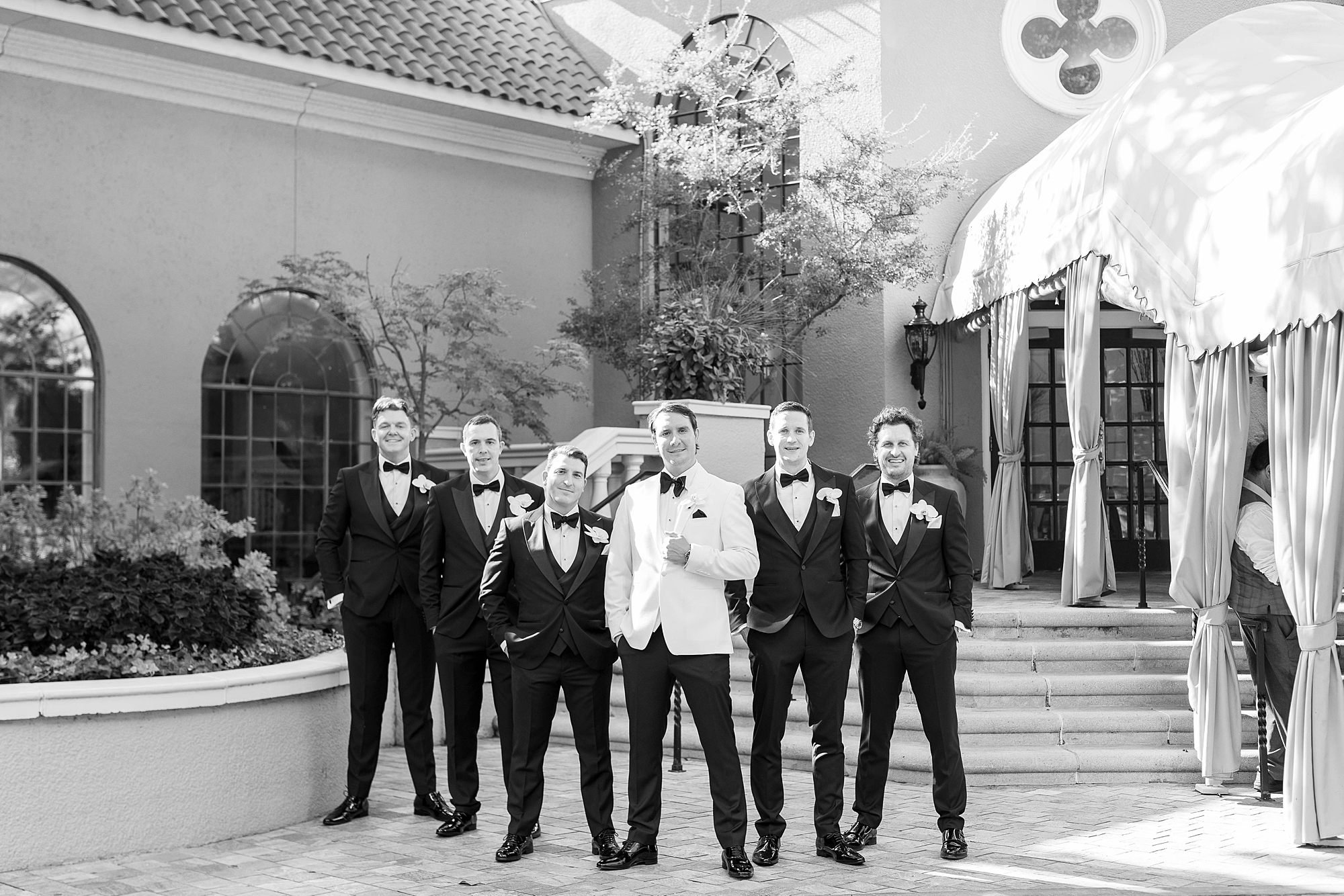 groom and groomsmen pose outside Rosewood Mansion near steps