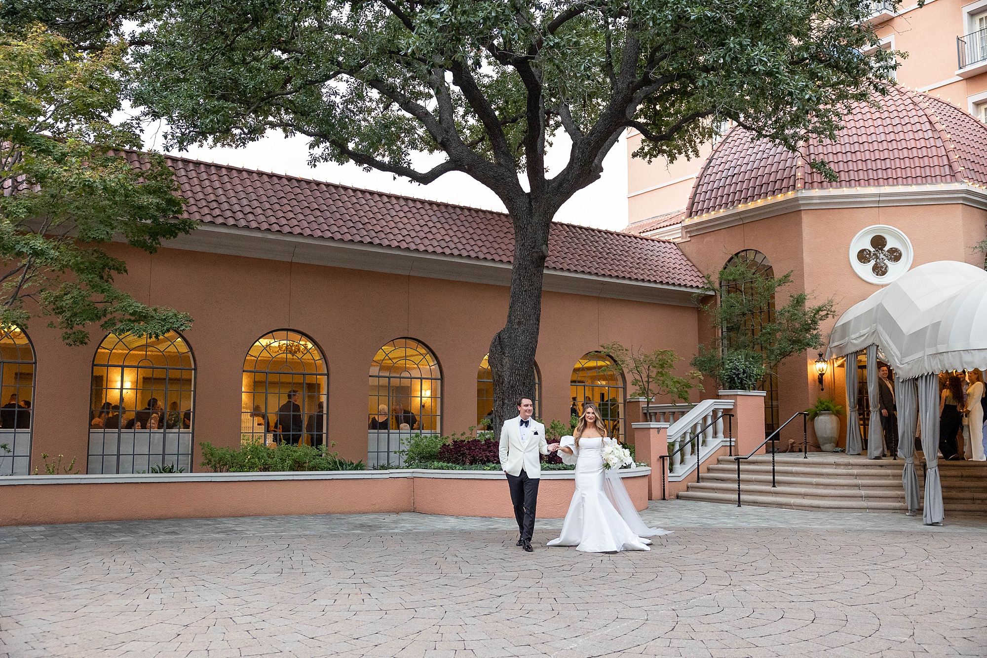 bride and groom hold hands walking across patio at Rosewood Mansion