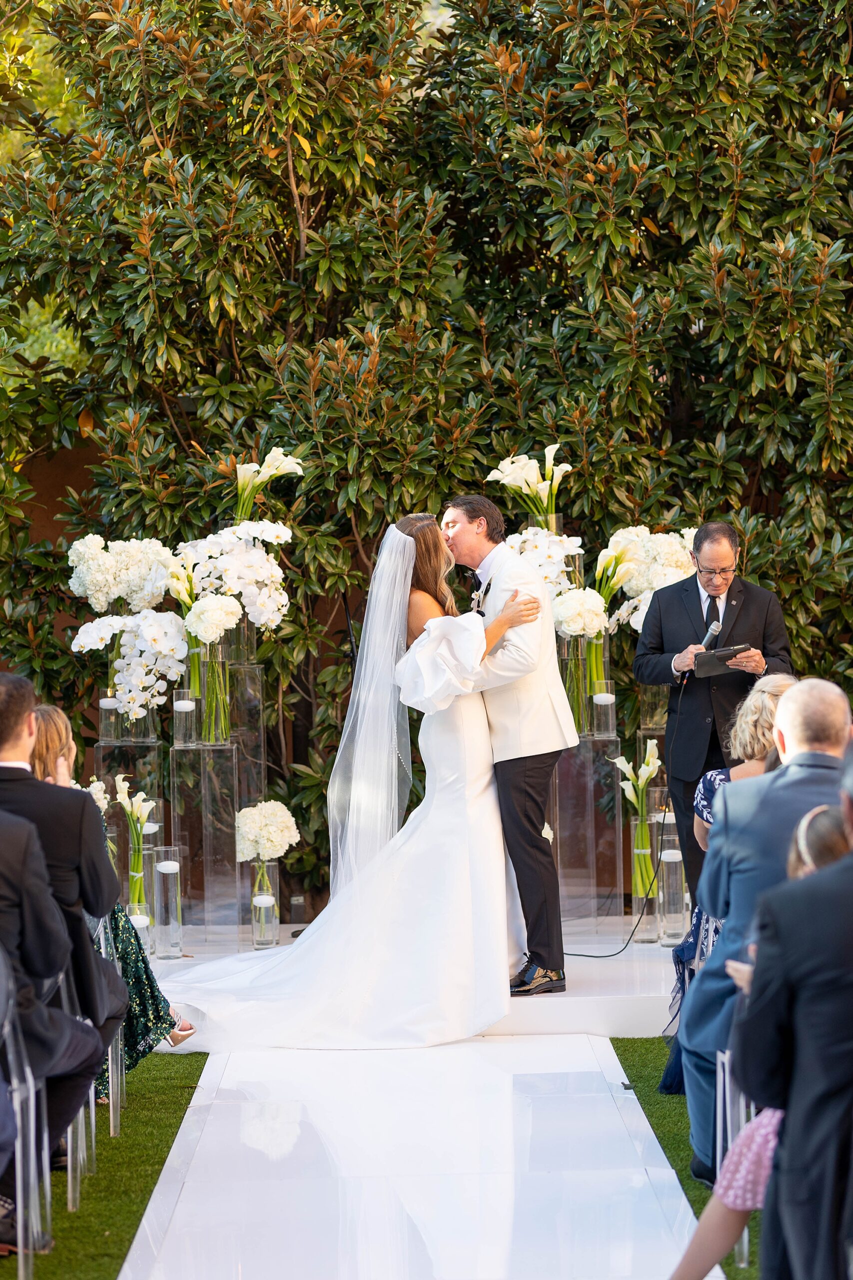 newlyweds kiss at end of the aisle on lawn at Rosewood Mansion