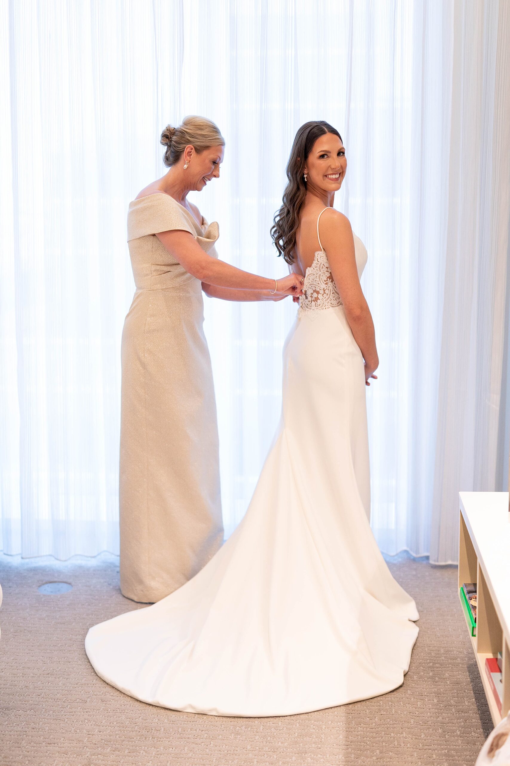 mother helps bride get into wedding dress in Dallas hotel 