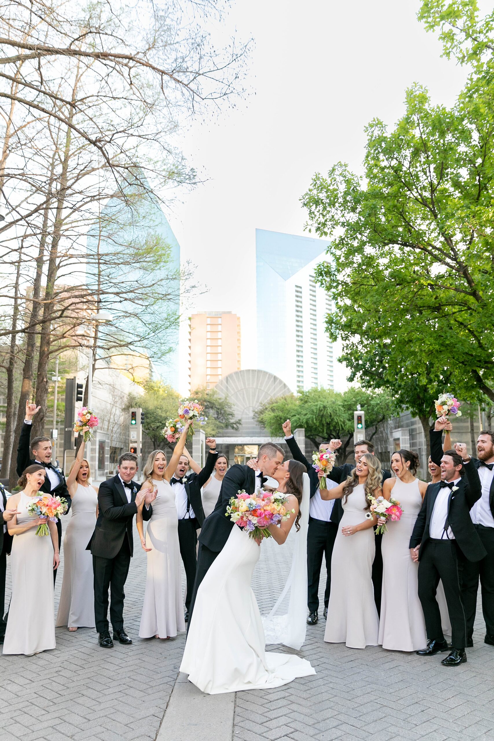 groom dips bride kissing her inside the Nasher Sculpture Center in front of wedding party 
