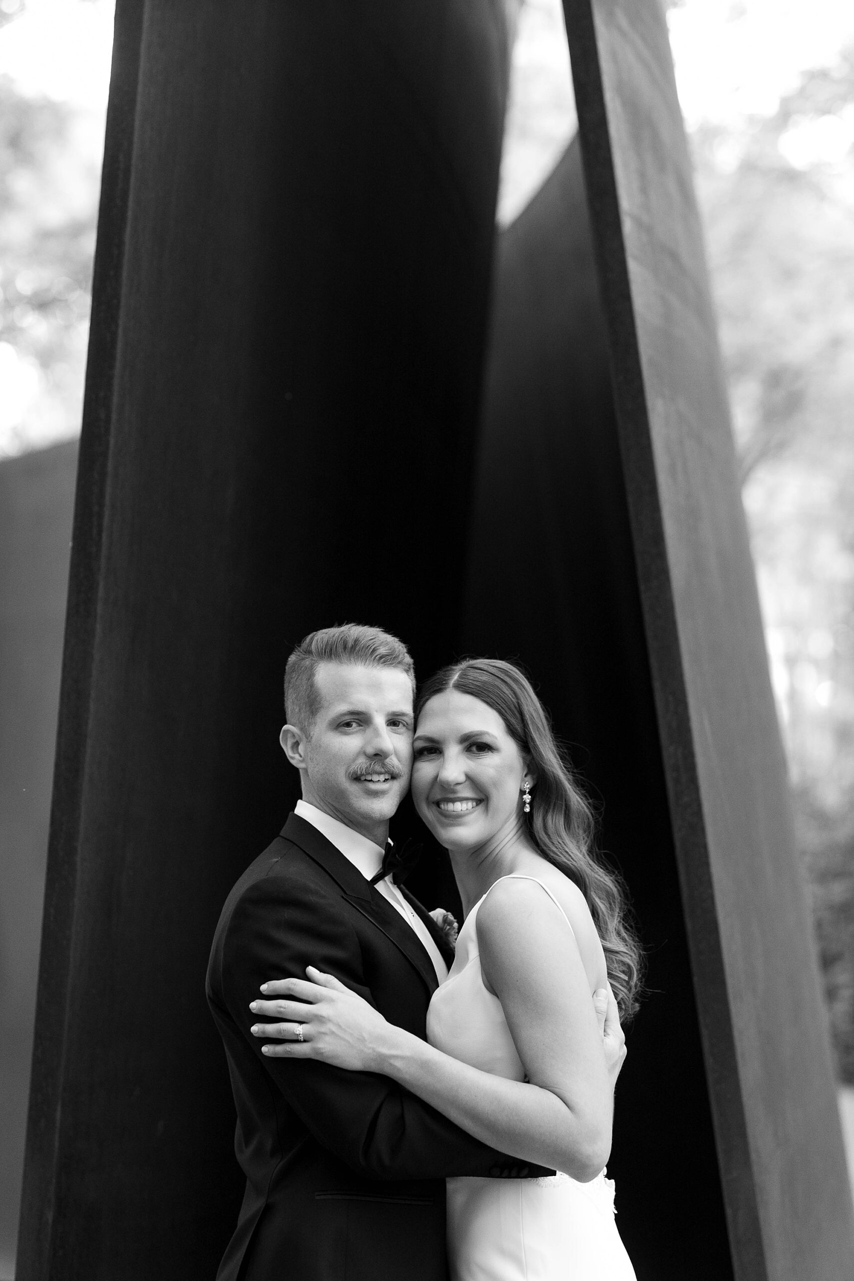 bride and groom hug in front of tall sculpture in the Nasher Sculpture Center