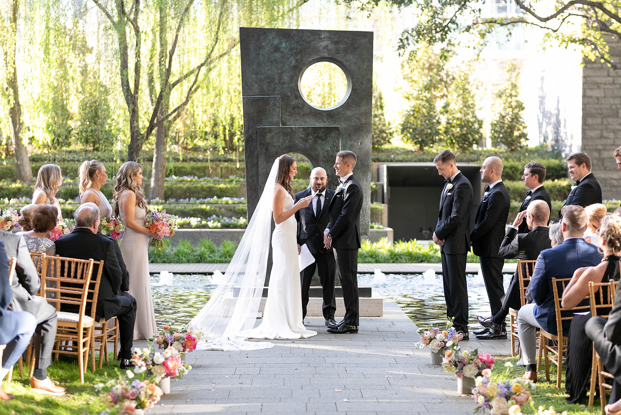 bride and groom hold hands inside the Nasher Sculpture Center during wedding ceremony 
