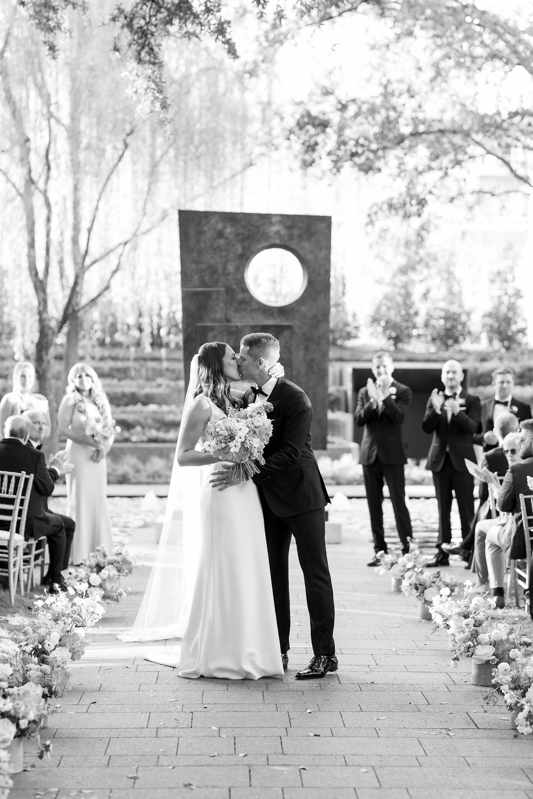 bride and groom walk up aisle to kiss after ceremony at the Nasher Sculpture Center