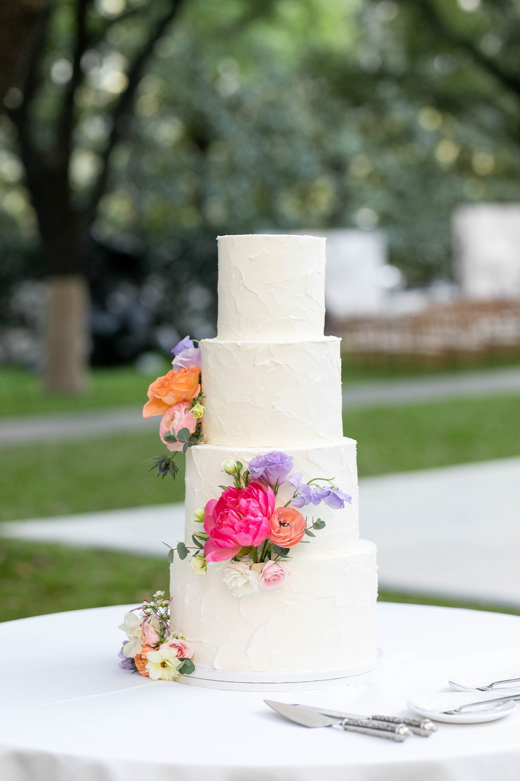 tiered wedding cake with bright flowers on side at al fresco wedding reception the Nasher Sculpture Center