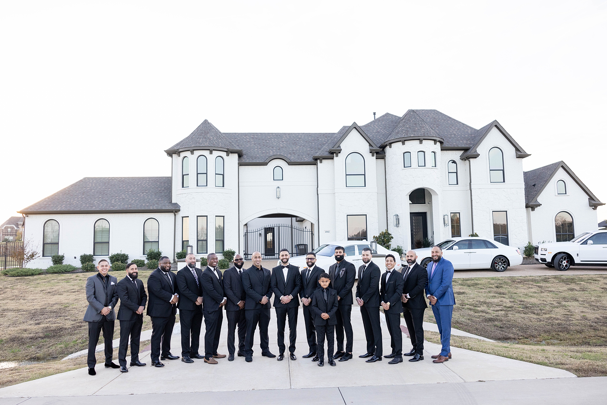groom and groomsmen stand outside white home in Dallas 