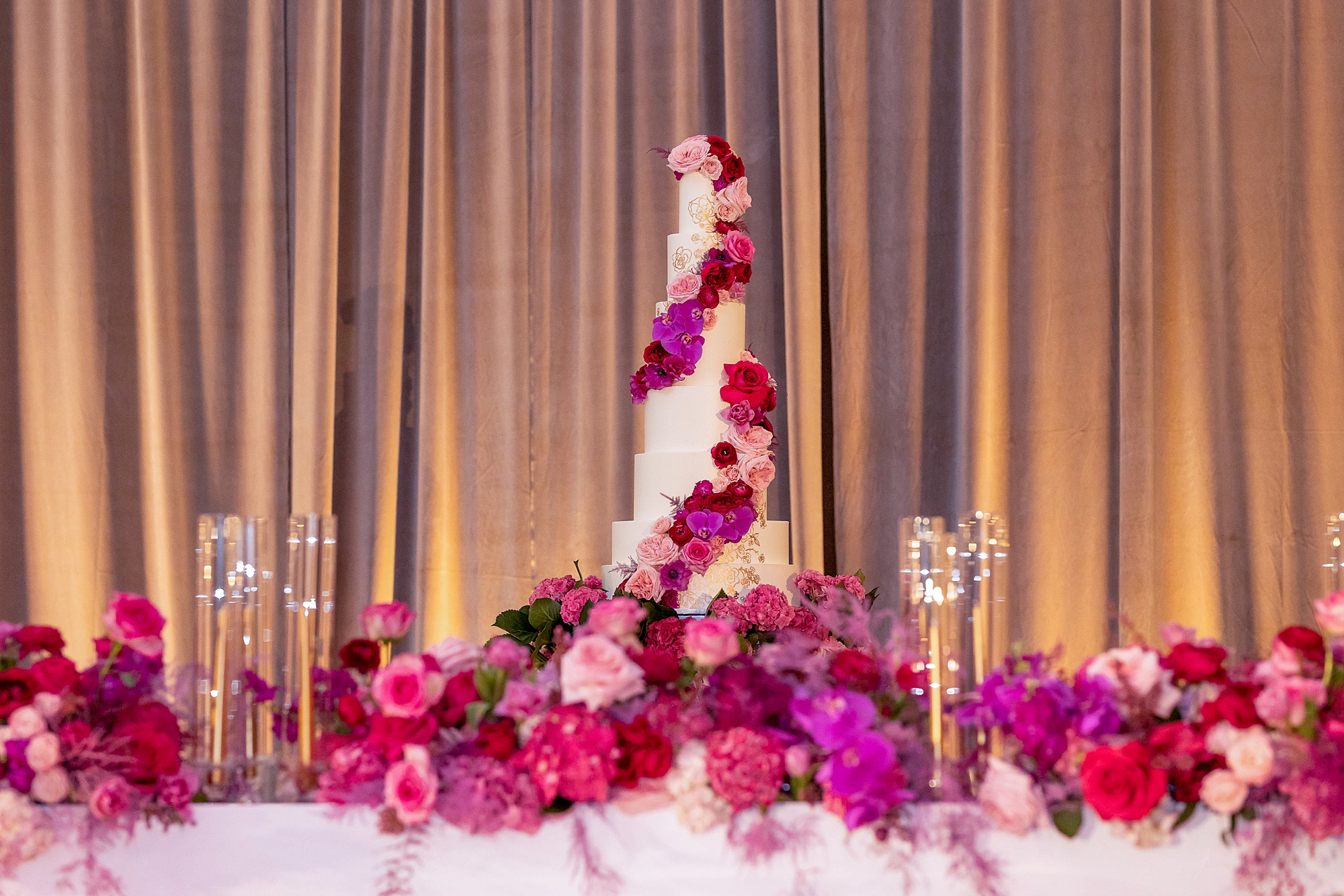 tiered wedding cake with pink flowers winding around the tiers 