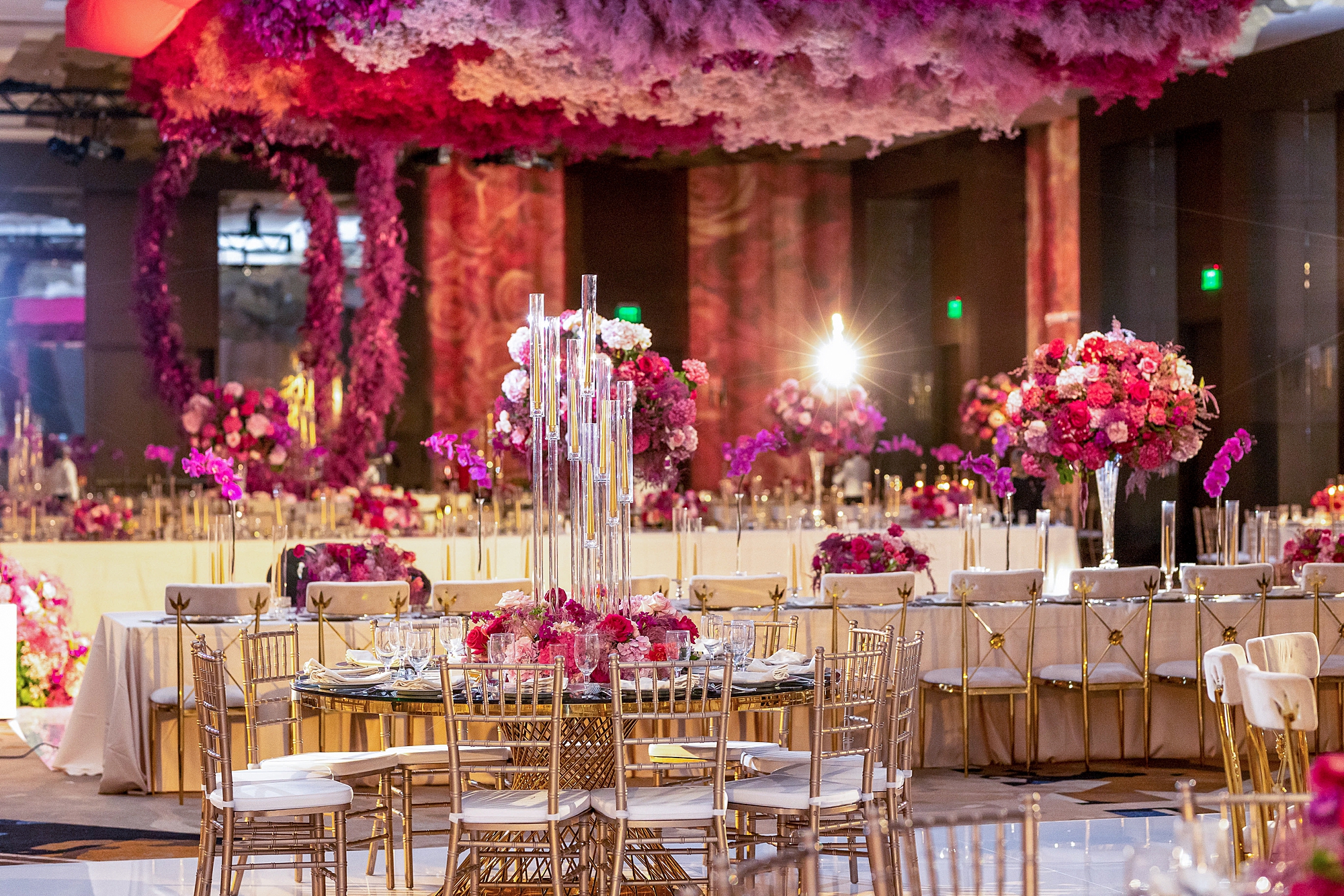 luxurious wedding reception with bright pink flowers on table and hanging 