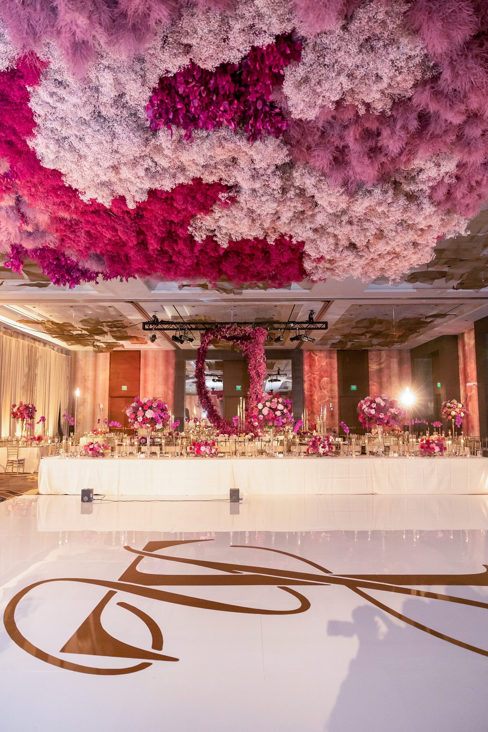 custom dance floor with gold lettering under bright pink flower installation at the Omni Frisco at the Star
